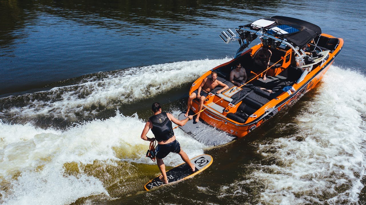 Group enjoying a thrilling wakeboarding session behind a motorboat on a sunny summer day.