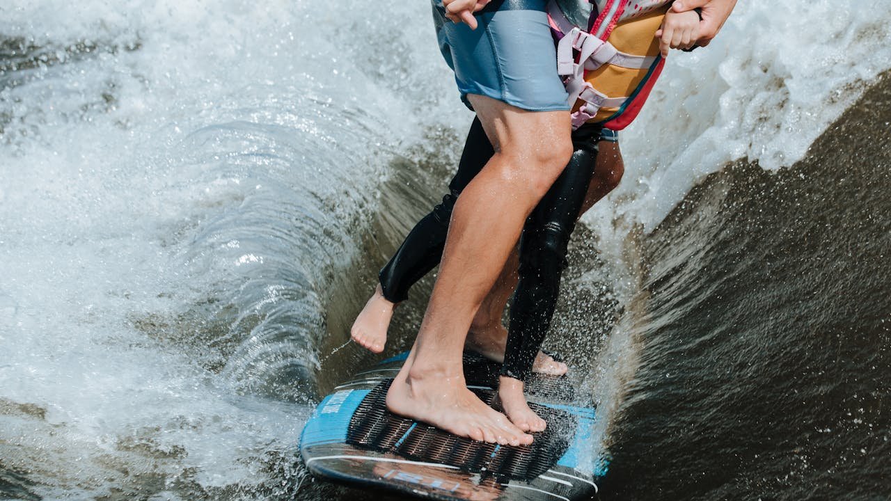 Two people enjoying a thrilling wake surfing adventure on a sunny summer day.